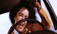 a woman is driving a car and holding the steering wheel with her mouth open