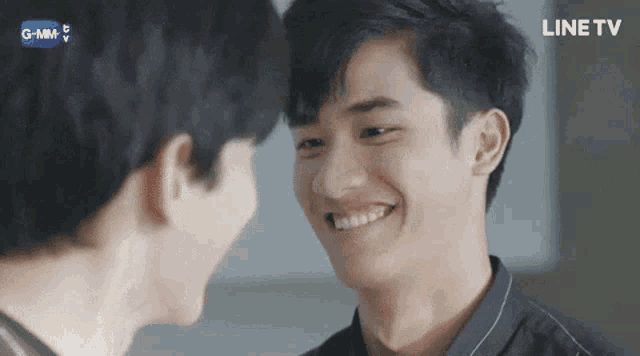 two young men are looking at each other and smiling while standing next to each other .