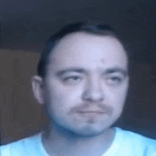 a close up of a man 's face with a blue shirt on .