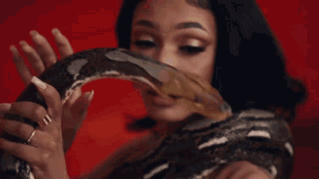 a woman holding a snake with a tattoo on her arm