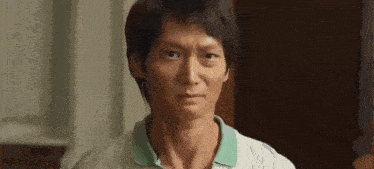 a close up of a man 's face with a striped shirt and a green collar .