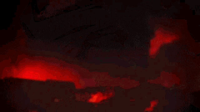 a person is holding a sword in their hand in a dark room with red lights coming out of it .