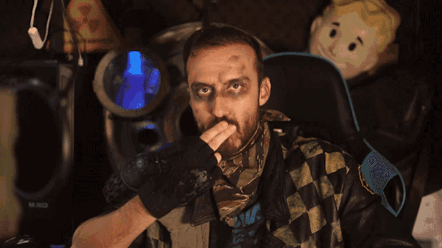 a man sitting in a chair with a vault boy doll behind him