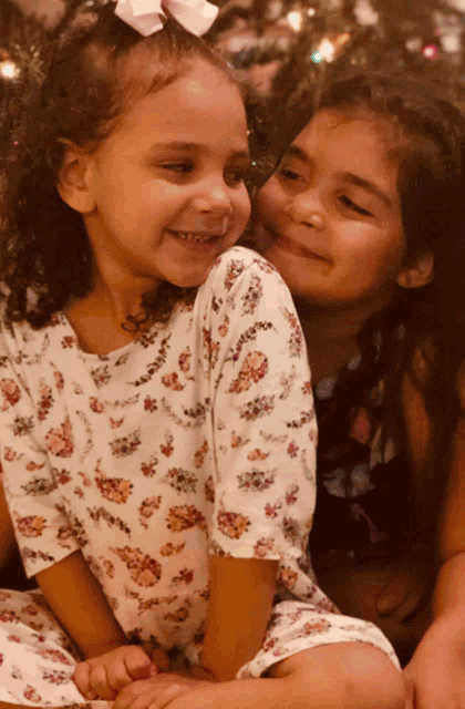 two little girls are sitting next to each other smiling