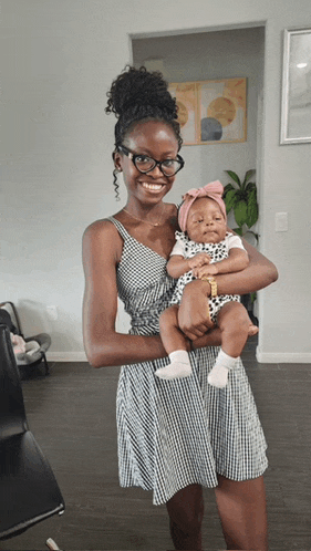 a woman in a plaid dress is holding a baby in her arms