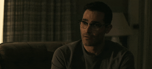 a man wearing glasses is sitting on a couch