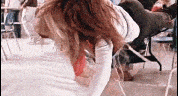 a woman is kneeling down in front of a crowd of people in a room .