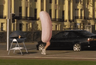 a person wearing a sausage costume is running down a street