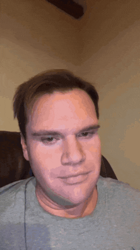 a man in a grey shirt is making a face