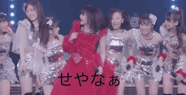 a girl in a red dress stands in front of a group of girls in silver outfits