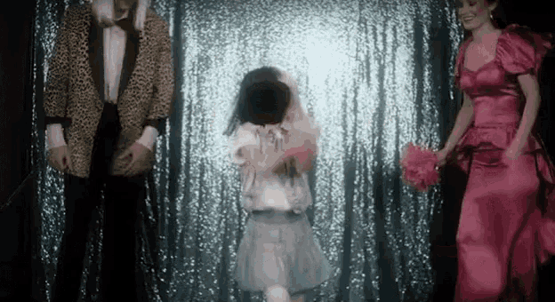 a man in a leopard print jacket and a woman in a pink dress are standing next to a little girl in a tutu .