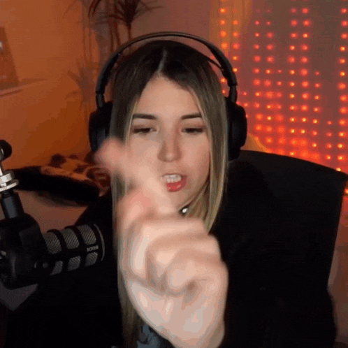 a woman wearing headphones is pointing her finger at the camera