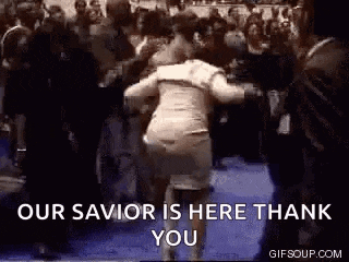 a woman is dancing in front of a crowd of people and a sign that says `` our savior is here thank you '' .