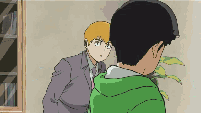 a man in a suit and tie stands next to another man in a green sweatshirt