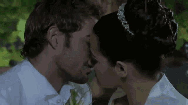 a bride and groom kissing in front of a green background