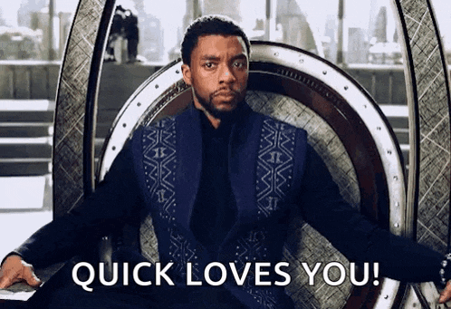 a man in a black suit is sitting in a chair with the words `` quick loves you '' written on it .