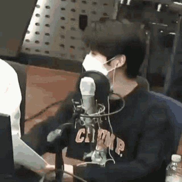 a man wearing a mask is sitting in front of a microphone in a radio station .