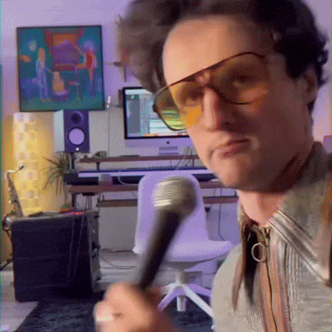 a man wearing sunglasses is holding a microphone and making a funny face