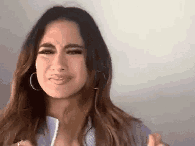 a woman with long hair and hoop earrings is crying .