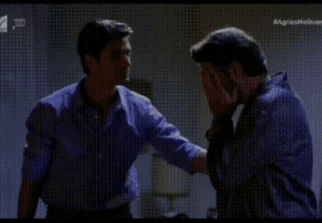 a man is covering his face with his hand while another man looks on ..
