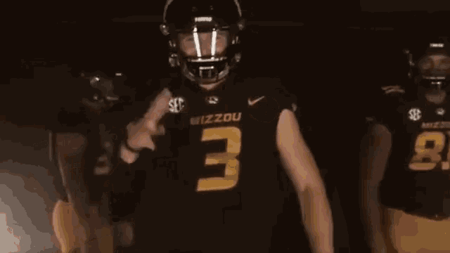 a mizzou football player wearing a black jersey with the number 3 on it