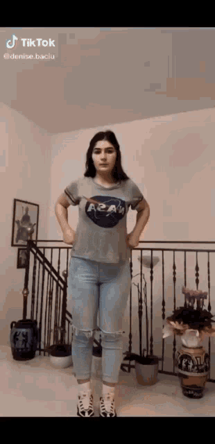 a woman wearing a nasa t-shirt is standing in front of a staircase
