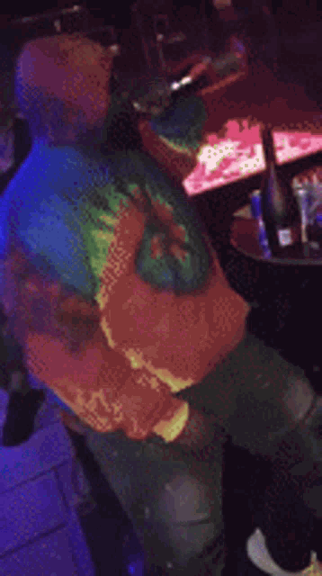 a blurry picture of a person in a tie dye shirt holding a bottle