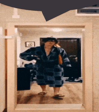 a person in a blue plaid robe stands in front of a mirror