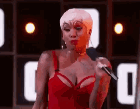 a woman in a red dress is singing into a microphone on stage .