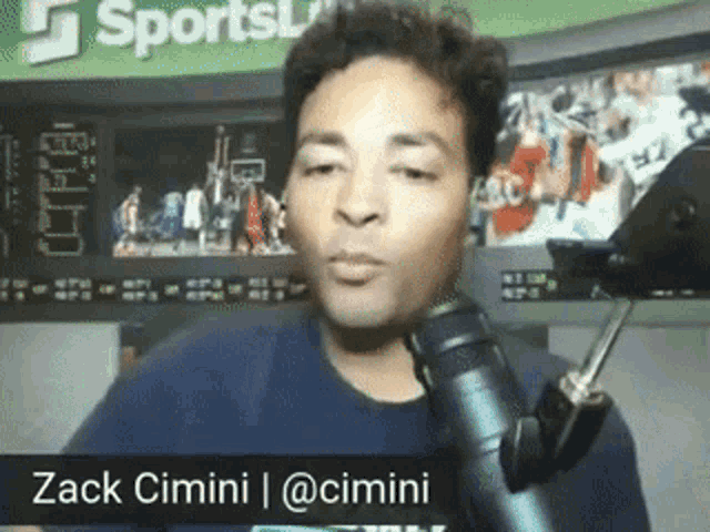 a man speaking into a microphone with the name zack cimini on the bottom right