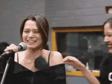 a woman singing into a microphone next to another woman