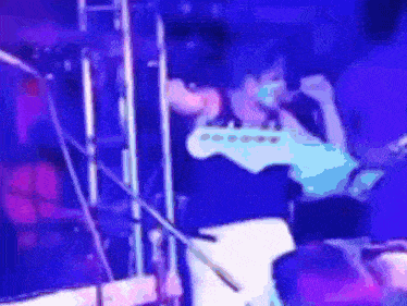 a blurry image of a person playing a guitar on stage