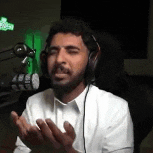 a man wearing headphones is sitting in front of a microphone and making a face .