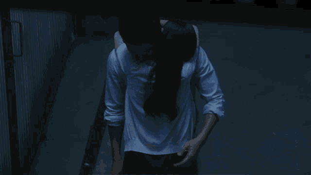 a man in a white shirt is hugging a woman in a dark room