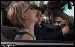 a woman driving a car with a child behind her
