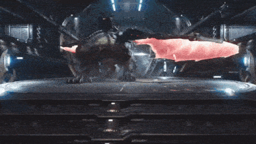 a dragon with red wings is standing on a platform in a dark room