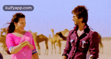 a man and a woman are standing next to each other in the desert and the website kulfyapp.com is visible in the corner