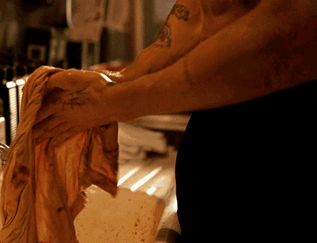 a man with a tattoo on his arm is washing a piece of cloth
