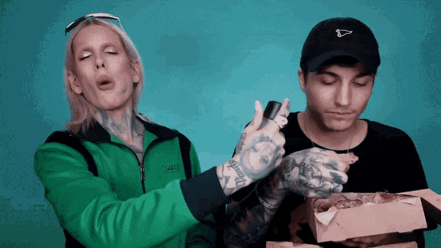 a man with a tattoo on his arm is holding a box of pizza next to another man