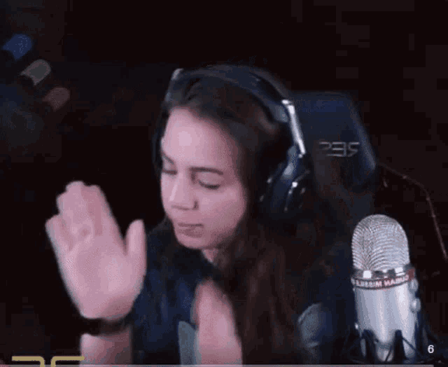 a woman wearing headphones is sitting in front of a microphone with the number 235 on it