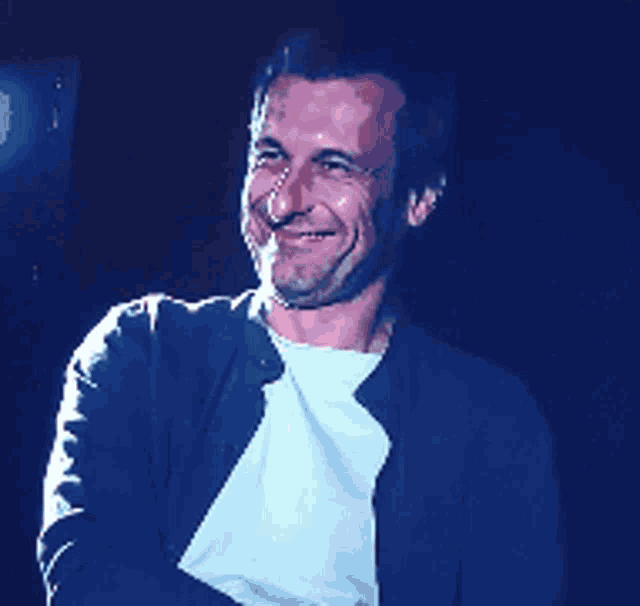 a man wearing a black jacket and white shirt is smiling