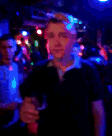 a man holding a glass of beer in a dark room