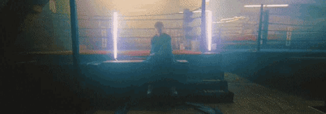 a man is sitting on a bench in a boxing ring in a gym .