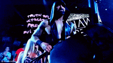a man in a hood stands in front of a sign that says " truth will ultimately prevail but the "