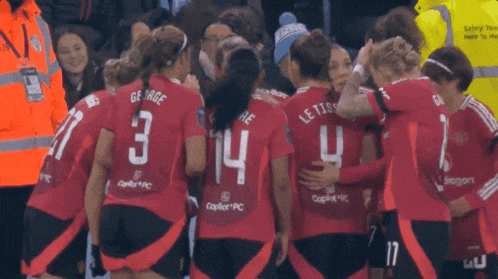 a group of female soccer players are huddled together and one of them has the number 14 on her back