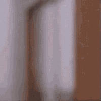 a blurry picture of a person peeking out from behind a wall .