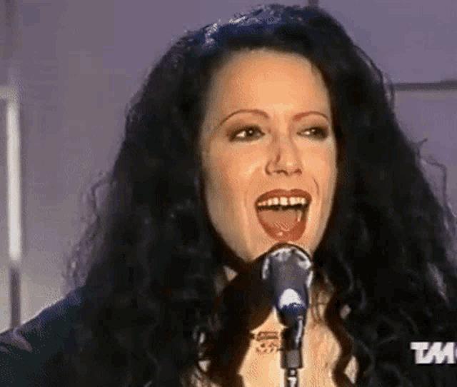 a woman singing into a microphone with a tm logo in the corner