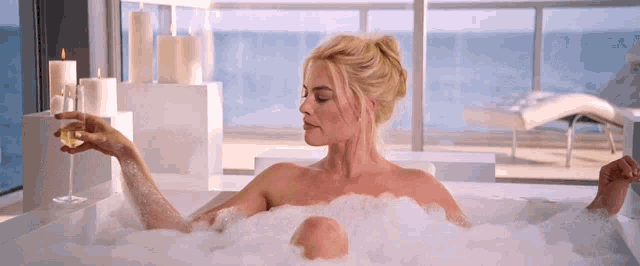 a woman is taking a bath with a glass of wine