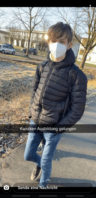 a young man wearing a mask and a black jacket is standing on a street