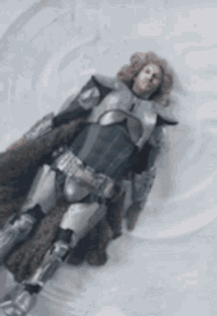 a man in armor is laying on the ground in the snow .